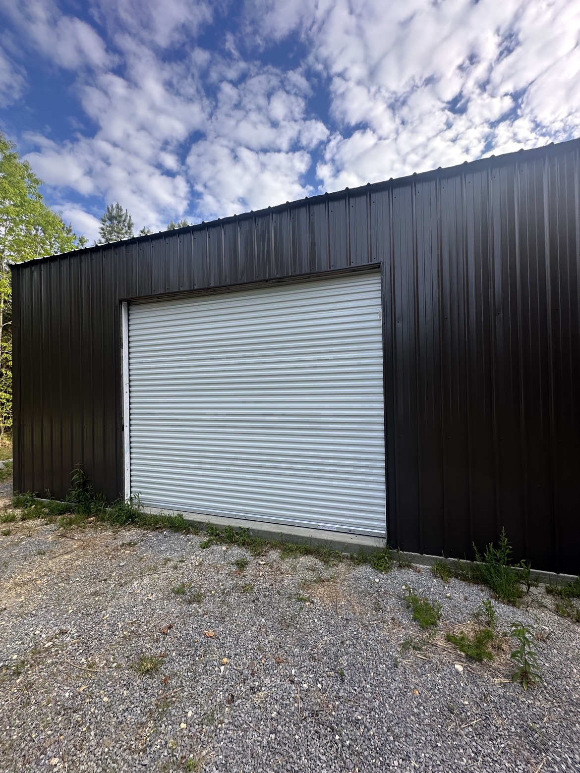White Janus roll-up door installed on a black metal building