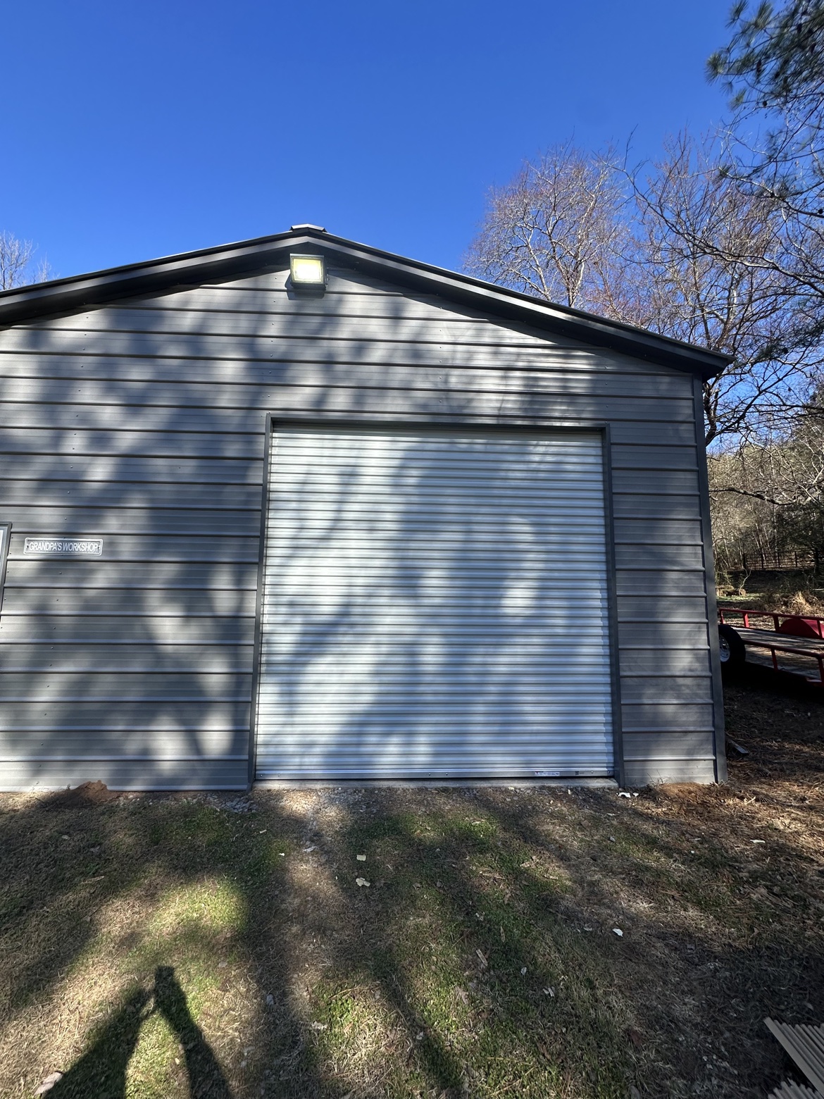 White roll-up door installed on a gray metal workshop