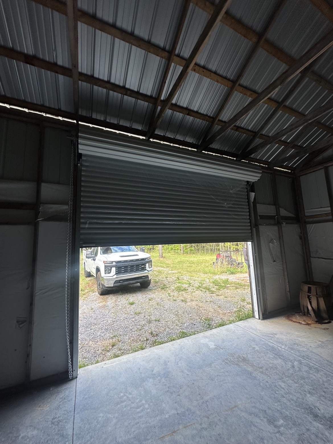 Partially open Janus roll-up door inside a metal building with chain hoist visible