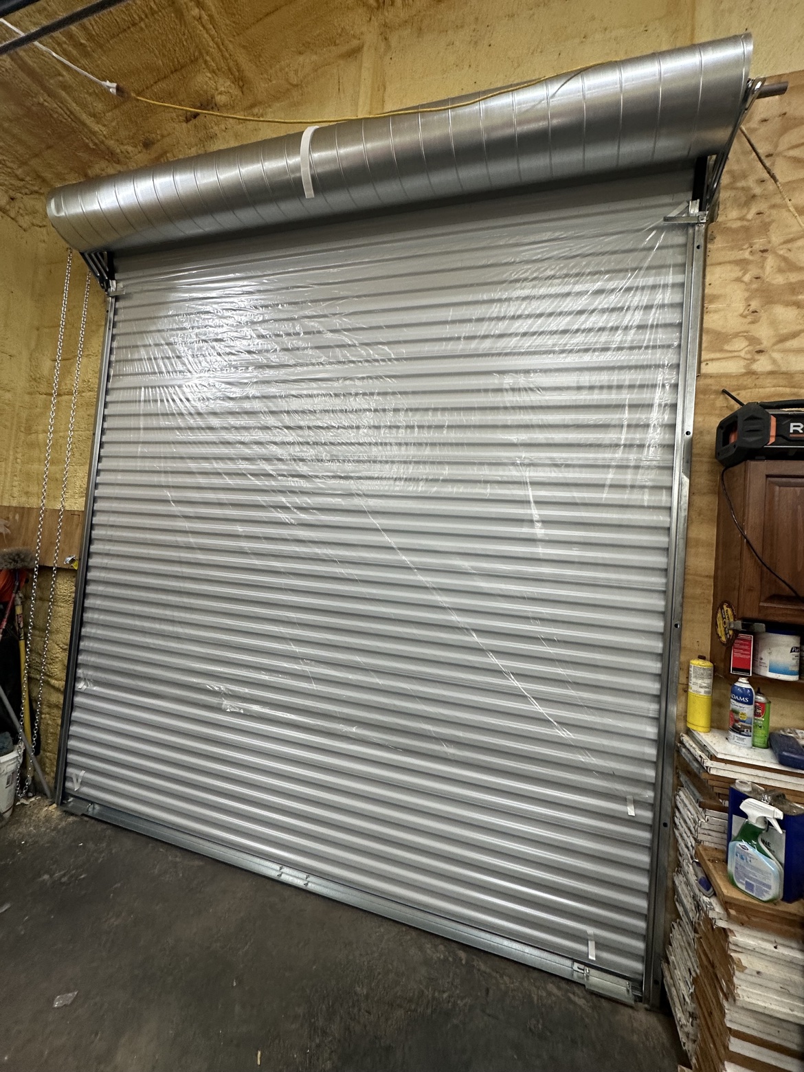 Large Janus roll-up door with chain hoist and protective film on the curtain