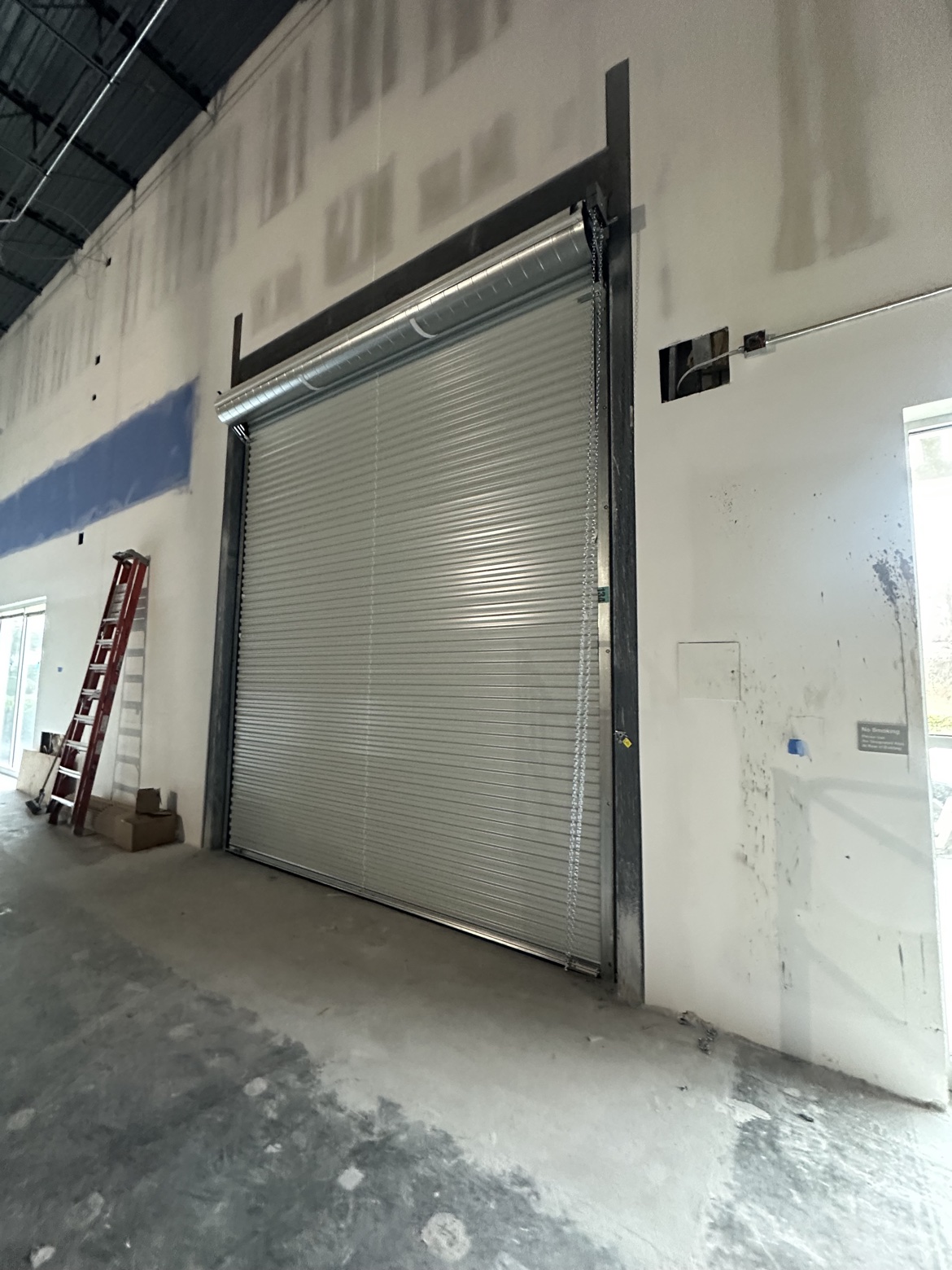 Large commercial roll-up door with chain hoist inside a warehouse