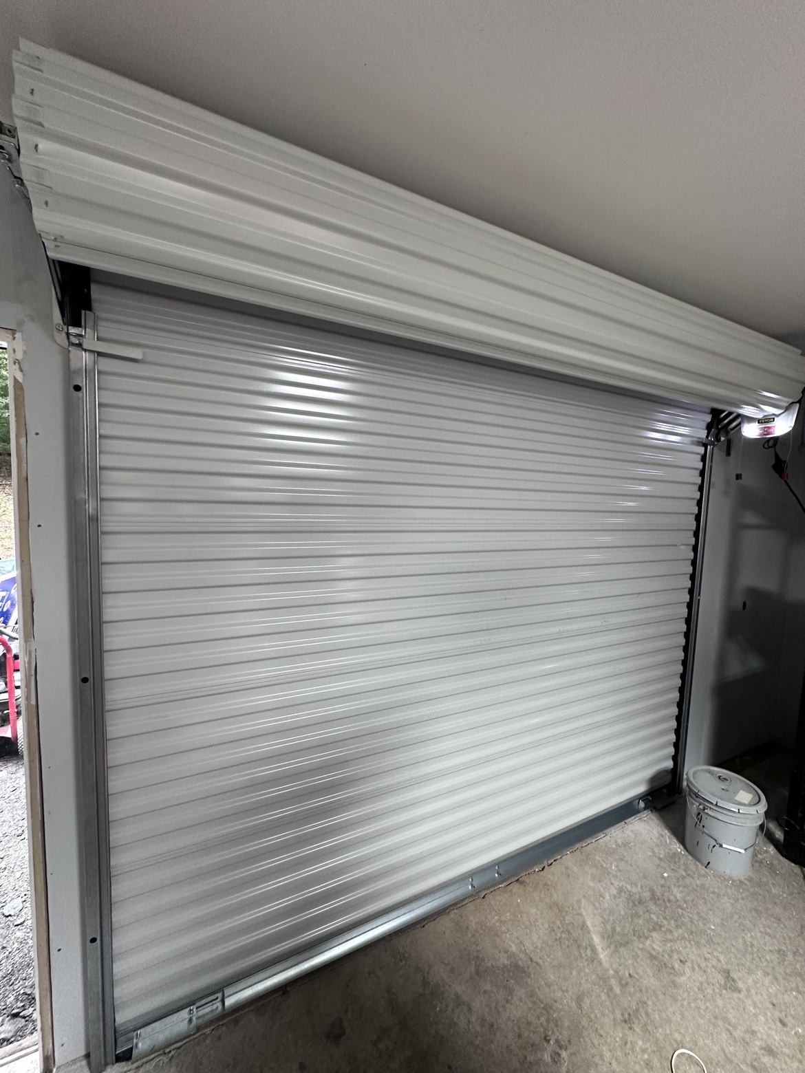 Interior view of a white Janus commercial roll-up door with barrel and guides visible